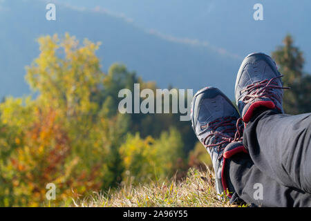 Beine der weiblichen Wanderer auf dem Gipfel mit spektakulären Blick auf Herbst Wälder im Hintergrund Stockfoto