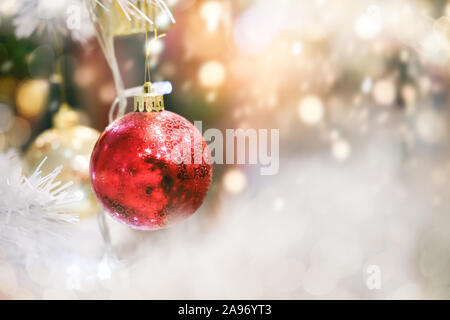Feiertage und weihnachten im Hintergrund. Glänzende weihnachtskugel hängt an Kiefernzweigen. Stockfoto