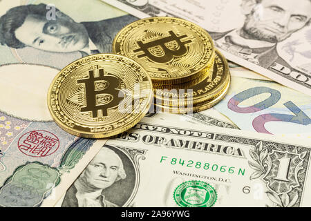 Nahaufnahme von vier Bitcoin cryptocurrency Münzen auf US-Dollar, japanischen Yen und Euro Banknoten festgelegt Stockfoto