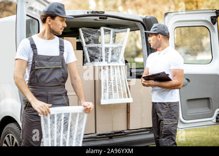 Lieferung Unternehmen Mitarbeiter abladen Cargo van Fahrzeug, liefern einige Güter und Möbel zu einem Kunden Startseite. Umzug und professionelle Lieferung Konzept Stockfoto