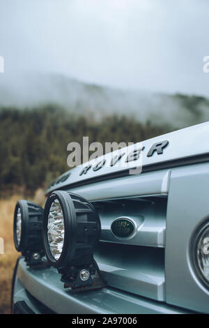 Den vorderen Grill eines Land Rover mit Nebel und die Berge im Hintergrund. Stockfoto