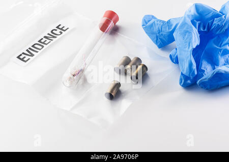 Nahaufnahme von 9 mm bullet Fälle in Evidenz Beutel, Fasern aus Glas Rohr und blau Handschuh auf weißem Hintergrund. Kriminalität, forensische Medizin, Untersuchung Stockfoto