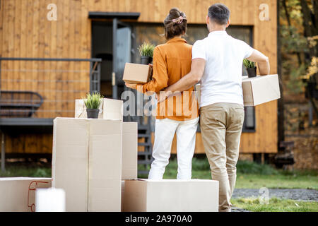Junges Paar zurück stehend mit Kartons vor ihrem neuen Haus. Konzept der Umzug in ein neues Zuhause. Stockfoto