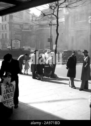 Ein Zeitungsverkäufer und Blumenverkäufer, der 1952 auf der Holborn-Station in London die Straße arbeitete. Eine Street-Szene aus den 1950er Jahren im Alltag mit Oldtimern im Hintergrund. Stockfoto