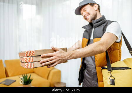 Professionellen Kurierdienst in Uniform holding Pizzakartons, Lieferung von Nahrung home Stockfoto