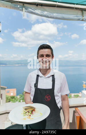 Kellner mit einer Platte, Konoba Nada, auf der Insel Krk, Kroatien Stockfoto