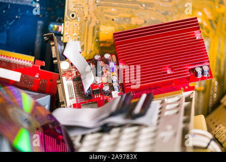 Ausrangierte Computer Hardware auf e-Halde. Verwendet oder veraltete PC-Teile. Rote Grafik karte, Kühlkörper, Kabel und elektronische Bauteile auf der Platine. Stockfoto
