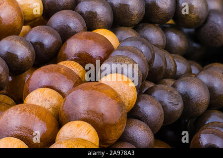 Runden hölzernen aufgereihte Perlen in Haufen, der an einem wunderschönen künstlerischen Hintergrund verheddert. String in Beige und Braun bemalt Kugeln verschiedener Größe lackiertem Holz. Stockfoto