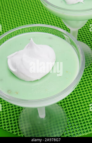 Overhead shot Hausgemachte grüne Pistazien Pudding mit einem Klacks Schlagsahne auf die Oberseite in zwei Frosted margarita Gläsern serviert. Natürlich beleuchteten Stockfoto