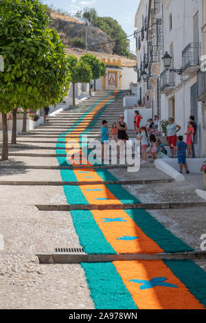 Bunte Teppiche von Holzhackschnitzeln in den Straßen, die von der Gemeinde während der Fronleichnam 2019, Carcabuey, Cordoba, Andalusien. Spanien Stockfoto