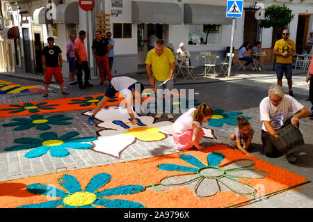 Gemeinschaft Herstellung von bunten Teppichen aus Holzhackschnitzeln in den Straßen der Stadt während Corpus Christi 2019, Carcabuey, Cordoba, Andalusien. Spanien Stockfoto