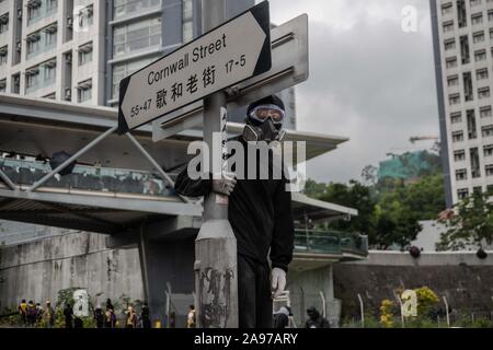 Eine Demonstrantin Uhren Cornwall Street in der Umgebung der Stadt Universität Hongkong während der Demonstration. Demonstranten für einen Tag von Streik und Pendler genannt, Chaos und Verzögerungen in Hongkong für den zweiten nachfolgenden Tag als anti-government Protesters Straßen-, Bahn- und U-Bahn greift auf einen Anruf für Streik blockiert. Unruhen brachen bei drei Universitäten und viele Schulen und Geschäfte geschlossen waren. Gewalt zurück in einer Antwort zu polizeilichen Maßnahmen auf Montag, wenn mindestens zwei Demonstranten erschossen wurden und viele andere Verletzte. Stockfoto