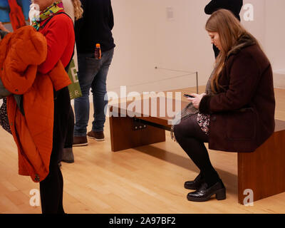 Prüfen ihr Telefon in einer Kunstgalerie Stockfoto