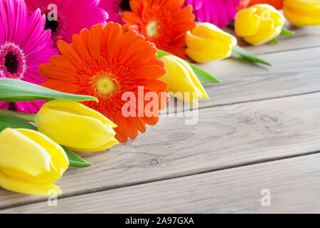 Blumenstrauß aus Gerbera Blumen und Tulpen gegen Holz- Hintergrund Stockfoto