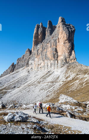 Drei Touristen gehen unter die Südwand der Tre Cime di Lavaredo / Drei Zinnen, Berggipfel in der Sexten Dolomiten, Südtirol, Italien Stockfoto