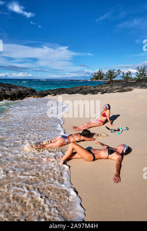 Drei Freunde genießen die Wellen und Sand auf Makalawena Strand, Hawaii Stockfoto