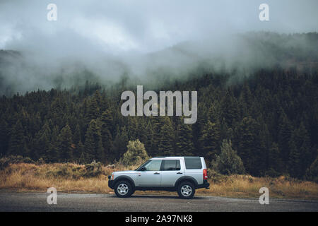 Ein Land Rover LR3 ist vor einem Berg im Nebel geparkt. Stockfoto