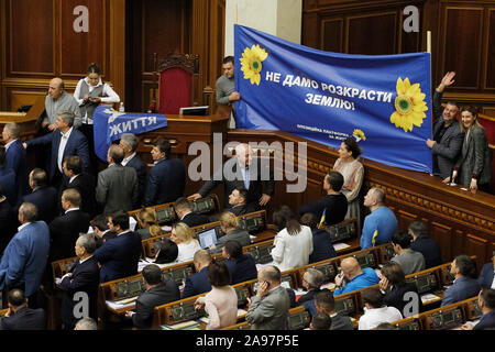 Kiew, Ukraine. 13 Nov, 2019. Ukrainische Gesetzgeber halten ein Banner zu, während andere eine Tribüne Block wie sie protestieren gegen Land Markt Bill während einer Sitzung des ukrainischen Parlaments (Werchowna Rada). Im September, das Kabinett einen Gesetzentwurf über die landwirtschaftlichen Flächen Markt zugelassenen vorgelegt und vom Parlament berücksichtigt werden, wie lokale Medien berichteten. Credit: SOPA Images Limited/Alamy leben Nachrichten Stockfoto