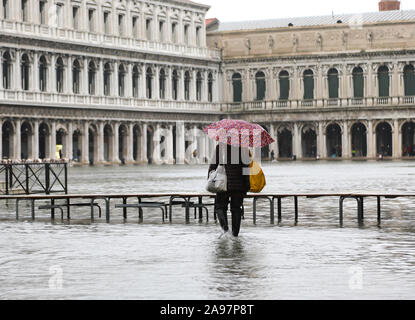 Person mit Regenschirm beim Hochwasser in Venedig in Italien und der Fussgängerzone boardway Stockfoto