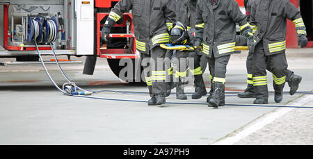 Vier Feuerwehrleute stretcher Bearer nach dem Unfall auf der Straße und die Fire Engine Stockfoto