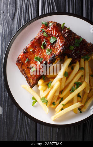 Gegrillte Rippchen serviert mit Pommes frites Close-up auf einem Teller auf den Tisch. Vertikal oben Ansicht von oben Stockfoto