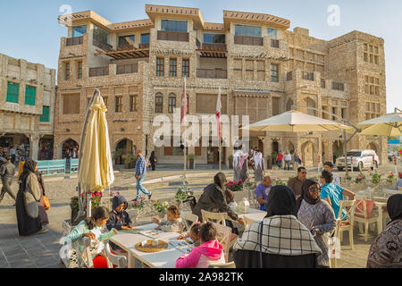 Frauen und Männer in den Souk Waqif zu Fuß auf der Straße und sitzen in einem Restaurant bei Tageslicht Stockfoto