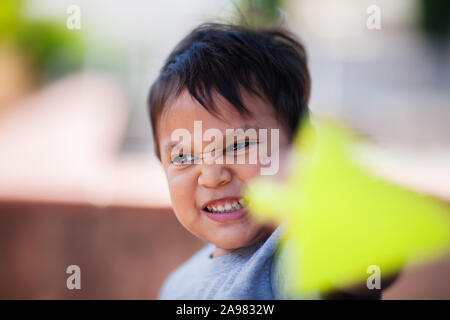 Ein süßer kleiner Junge spielt mit seinem Spielzeug und mit Hilfe seiner Phantasie in einem Außenbereich. Stockfoto