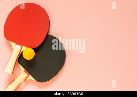 Schwarz und Rot Tennis ping pong Schläger und orange Kugel auf einem rosa Hintergrund isoliert, Sport Ausrüstung für Tischtennis Stockfoto
