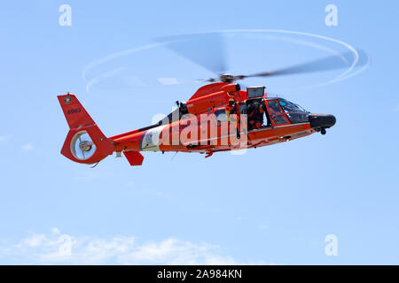 Ein uscg Schwimmer hängt von der Hebevorrichtung mit einem MH-65 Dolphin Helikopter Stockfoto