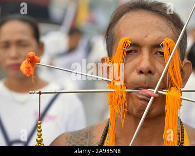 Im mittleren Alter Thai Chinesische taoistische Anhänger durchdringt seine obere Augenlider, seine Wangen und Zunge mit langen Stiften und Spieße während der Vegetarische Festival. Stockfoto