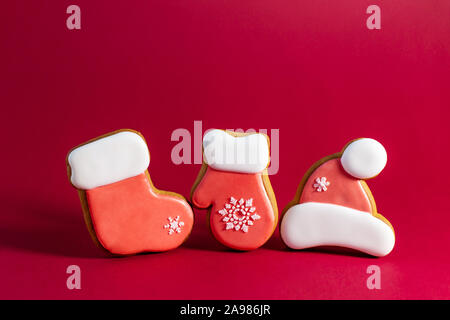 Lebkuchen Cookie von Santas Kleidung auf roten Hintergrund. Traditionelle Weihnachten essen. Weihnachten und Neujahr Urlaub Konzept Stockfoto