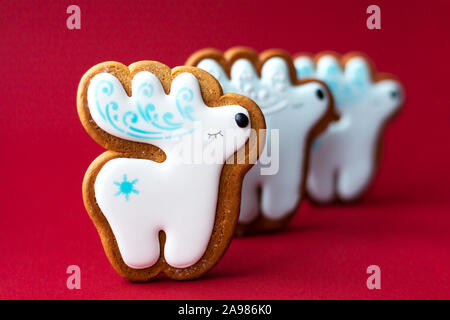 Lebkuchen Cookie von kleinen niedlichen Hirsche auf roten Hintergrund. Traditionelle Weihnachten essen. Weihnachten und Neujahr Urlaub Konzept Stockfoto