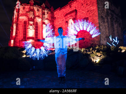 Edinburgh, Vereinigtes Königreich. 13 November, 2019 dargestellt: ein Performer spins Licht Steckt vor der Projektion auf die Burganlage auf der Burg von Licht. Das Edinburgh Castle startet seine Schloss des Lichtes, die vom 14. November bis 22. Dezember 2019. Credit: Rich Dyson/Alamy leben Nachrichten Stockfoto