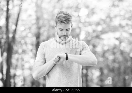 Zählen von Kalorien. Armband Gadget. Athlet prüfen Fitness tracker Natur Hintergrund. Athlet mit Borsten schaut Schrittzähler gadget Fortschritt führen. Sportler trainieren mit Smart watch Gadget. Stockfoto