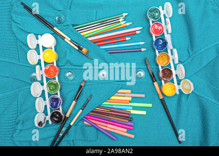 Bunte Bleistifte und gouache Dose mit Pinsel auf einem blauen pullover Flachbild Hintergrund legen. Stockfoto