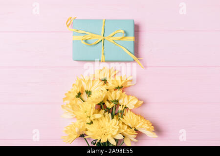 Festliche flach Zusammensetzung der Geschenkbox und einen Strauß Blumen auf rosa Hintergrund, Ansicht von oben. Stockfoto