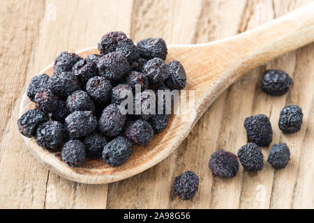 Getrockneten Aronia Beeren und Löffel aus Holz Stockfoto