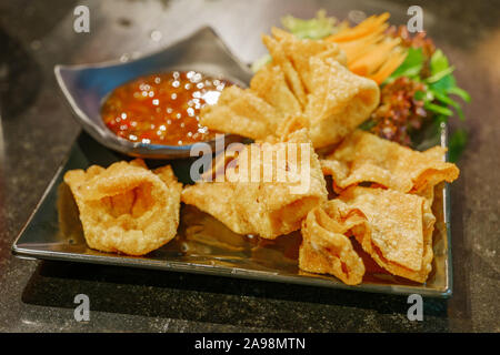 Dumping oder frittierte Wan-tan wrap Garnelen im Inneren, Dienen mit süßen Soße auf schwarze Keramikplatte. Stockfoto