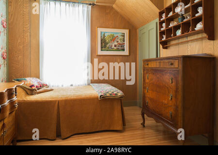 Einzelbett mit gefalteten Decke Decke, antike hölzerne Kommode im Erdgeschoss Schlafzimmer mit Birkenholz Dielen in einem alten 1920er Haus Stockfoto