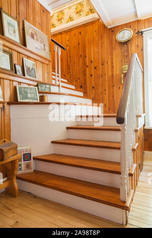 Kiefernholztreppe mit weiß bemalten Balustern führt in die obere Etage im Wohnzimmer mit Birkenholzböden in einem alten Haus aus den 1920er Jahren. Stockfoto