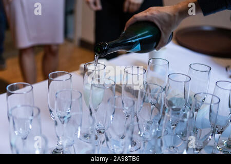 Selektiver Fokus einer Person gießt in alkoholische Getränke zu leeren, Kristallgläser, stehend auf einem weißen Gewand Buffet Tisch Stockfoto