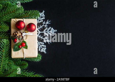 Urlaub Weihnachten Karte Hintergrund mit festlichen Dekoration Kugel, Sterne, Schneeflocken, Geschenkbox, Tannenzapfen auf schwarzem Hintergrund von Flach, Ansicht von oben. Stockfoto