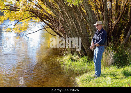 Ältere männliche Rentner im Urlaub Fliegenfischen auf Forellen in einem Fluss Stockfoto
