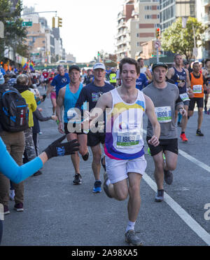 New York City Marathonläufer aus der ganzen Welt durch Nachbarschaft New Yorker entlang der 4th Avenue in Brooklyn, etwa 6 Meile Markierung ermutigt, während der 2019 in New York City Marathon. Stockfoto