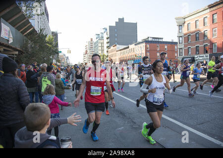 New York City Marathonläufer aus der ganzen Welt durch Nachbarschaft New Yorker entlang der 4th Avenue in Brooklyn, etwa 6 Meile Markierung ermutigt, während der 2019 in New York City Marathon. Stockfoto