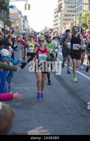 New York City Marathonläufer aus der ganzen Welt durch Nachbarschaft New Yorker entlang der 4th Avenue in Brooklyn, etwa 6 Meile Markierung ermutigt, während der 2019 in New York City Marathon. Stockfoto