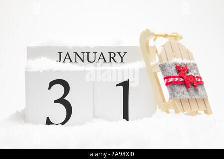 Holz- Kalender für Januar, der 31. Tag des Monats. Die Symbole der Winter Schnee und Schlitten. Konzept der Feiertage, Urlaub und Winter Spaß. Stockfoto