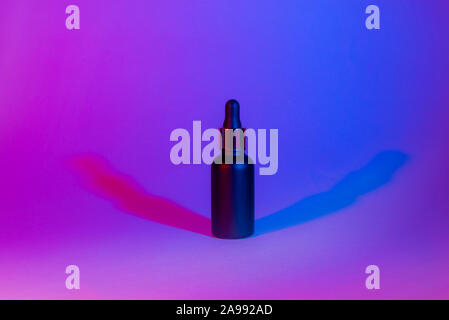 Eine Flasche schwarz matt Farbe auf einem Neon trend Hintergrund. Kosmetik Konzept. Minimum. Stockfoto