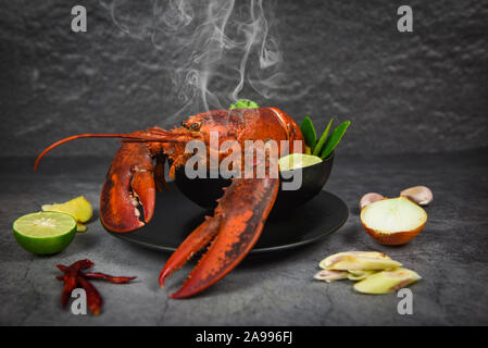 Red Lobster spicy Soup Bowl/gekochte Meeresfrüchte mit Hummer Dinner und Gewürze Zutaten auf schwarze Platte Thai Food Stockfoto