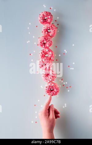 Kreative Bild der vollkommenen Balance, Turm oder der Pyramide von leckeren Rosa donuts Balancieren auf Zeigefinger der Hand. Beliebte chanukah Dessert. Anhand von quantitativen Simulatio Stockfoto